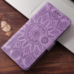 Purple embossed phone wallet case with mandala pattern resting on a laptop keyboard tray | Levné Kryty